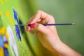 Close-up Shot of Female Artist Hand, Holding Paint Brush and Drawing Oil Painting. Contemporary Painter Creating Modern