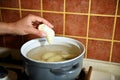 Close-up shot of female hand of pastry chef dipping cherry dumplings into a pot of boiling water. Process of cooking dumplings