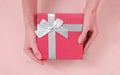 Close up shot of female hands holding a small gift wrapped with blue ribbon. Small gift in the hands of a woman indoor Royalty Free Stock Photo