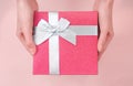 Close up shot of female hands holding a small gift wrapped with blue ribbon. Small gift in the hands of a woman indoor Royalty Free Stock Photo