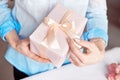 Close-up shot of female hands holding a small gift wrapped with pink ribbon. Small gift in the hands of a woman indoor Royalty Free Stock Photo