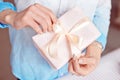 Close-up shot of female hands holding a small gift wrapped with pink ribbon. Small gift in the hands of a woman indoor Royalty Free Stock Photo