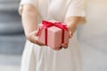 Close up shot of female hands holding a small gift wrapped with pink ribbon. Small gift in the hands of a woman indoor. Shallow Royalty Free Stock Photo