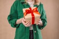 Close up shot of female hands holding a small gift wrapped with red ribbon. Gift in the hands of a woman indoor. Shallow Royalty Free Stock Photo