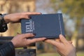 Close up shot of female hands and a male hand holding the Bible on a blurred background Royalty Free Stock Photo