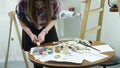 Close-up shot of female hands squeezing out a tube of paint onto the palette