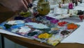 Close-up shot of female hands squeezing out a tube of paint onto the palette