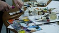 Close-up shot of female hands squeezing out a tube of paint onto the palette