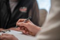 Close-up shot of a female professional writing something on a clipboard during a therapy session