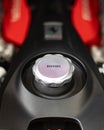 Close-up shot of a Ferrari aluminum oil cap with ferrari inscription with an engine on background