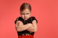 Close-up shot of a charming blonde little lady in a combined dress posing against a pink background.