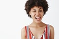 Close-up shot of flirty emotive and playful african american with afro hairstyle sticking out tongue and winking