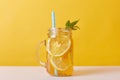 Close up shot of fresh drink with lemons and mint, glass jug filled with cocktail and lemon slices and drinking tube, cold summer