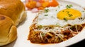 Close up shot of a fried egg on Indian thick gravy with buns and salad Royalty Free Stock Photo