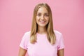 Close-up shot of friendly pleasant commong caucasian girl with fair hair and tanned skin in t-shirt smiling broadly with