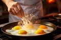 Close-up shot of frying pan on stove with fried eggs and cook\'s hand
