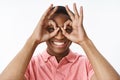 Close-up shot of funny and playful good-looking kind and happy african american guy showing okay gesture as binoculars