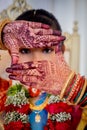 Close-up shot of a girl with colorful jewelry, posing with her hands in intricate henna designs