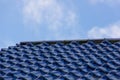 Close-up shot of a glazed blue tiled roof with a blue sky in the background