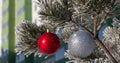 Close up shot of a glittering white and blurred shiny red Christmas balls hanging off a Christmas fir tree outside, all partially Royalty Free Stock Photo