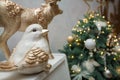 Close up shot of gold shiny reindeer and bird toys on white piano with unfocused fir-tree on background, decorated for Merry Royalty Free Stock Photo