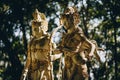 Close up shot of golden balinese statues with green nature background