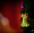 Golden glossy glitter bell with red ribbon hanging decorating on green Christmas pine tree Royalty Free Stock Photo
