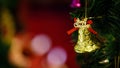 Golden glossy glitter bell with red ribbon hanging decorating on green Christmas pine tree Royalty Free Stock Photo