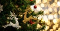 Close up shot of Golden and silver glossy Christmas eve decor reindeer jumping model hanging decorating on green Xmas pine tree Royalty Free Stock Photo
