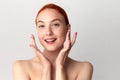 Close up shot of gorgeous girl with red hair and bare shoulders looking at camera and smiling on white studio background Royalty Free Stock Photo