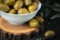 Close up shot of green olives in a white bowl on the wooden stand with olive leaves on a black background. Traditional Greek and Royalty Free Stock Photo