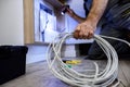 Close up shot of hand of aged electrician, repairman in uniform working, fixing, installing an ethernet cable in fuse