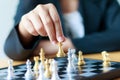 Close up shot hand of business woman moving golden chess to defeat a silver king chess on white and black chess board for Royalty Free Stock Photo