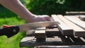 Close up shot of a hand cutting through a wooden board. A man uses a manual saw Royalty Free Stock Photo