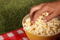 Hand Reaching into Bowl of Popcorn on Picnic Blanket