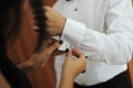 Caucasian woman helping business man or groom wearing vintage silver cuff links on white shirt while getting dressed Royalty Free Stock Photo