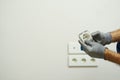 Close up shot of hands of electrician wearing protective gloves while installing wall plug socket in a new house