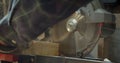 Close-up shot of hands of male senior carpenter carving the wood with headsaw into small squares at manufacture.