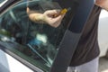 Worker removing old car window glass protective tint foil from side window Royalty Free Stock Photo