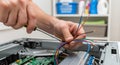 close-up shot of hands working on electrical wiring inside a computer case with a screwdriver, showcasing repair or maintenance Royalty Free Stock Photo