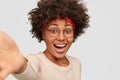 Close up shot of happy overjoyed Afro American woman with glad expression, stretches hand for making selfie portrait Royalty Free Stock Photo