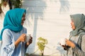 Close up happy shot two hijab women drinking tea and coffee in front of the house and smiling Royalty Free Stock Photo
