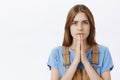 Close-up shot of hopeful serious-looking determined cute young woman with chestnut hair standing concerned holding hands