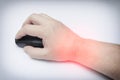 A close-up shot of a human hand operating a black wireless computer mouse on a clean white surface, with red spot on the wrist, Royalty Free Stock Photo