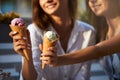 Close up shot of ice cream cones in hand of a woman standing with her friend. Two young women outdoors eating icecream Royalty Free Stock Photo