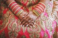 The hands of Indian bride with menhdi henna tattoo and bunch of glitter bangles on her wrist, close-up