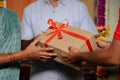 close up shot of Indian couple hands receiving parcel or gift box from delivery person at home - concept of online