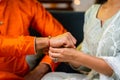 Close up shot of indian girl tying rakhi to brother hand during raksha bandhan festival at home - concept of indian