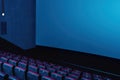 Close up shot of interior of cinema auditorium with lines of red chairs and big white screen Royalty Free Stock Photo