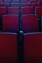 Close up shot of interior of cinema auditorium with lines of red chairs in front of a big screen